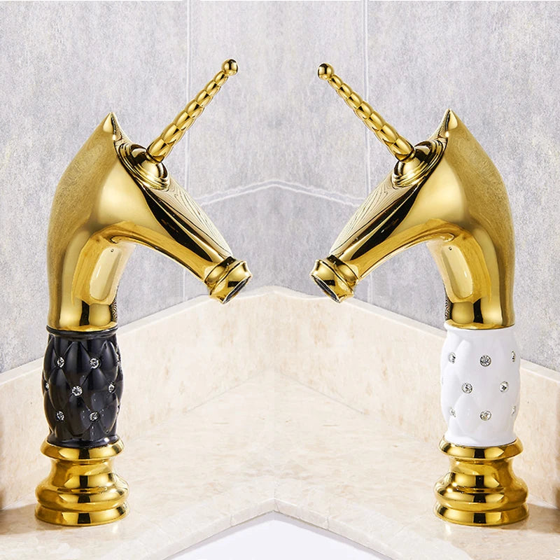 Two gold faucets with black and white handles on a marble countertop.