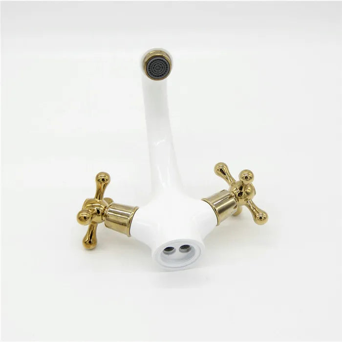 Gold faucet handles with white ceramic discs on a white background