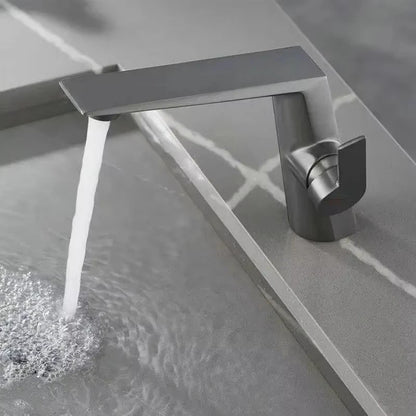 Modern silver faucet with water flowing into a bathtub.