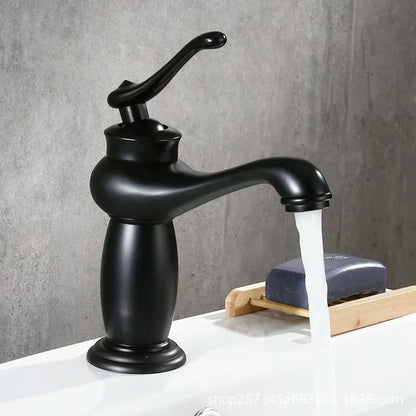 Black faucet with water flowing onto a white surface with a gray background
