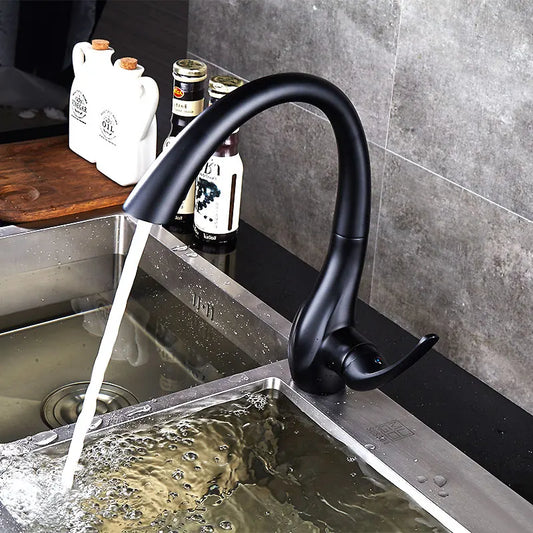 Black kitchen faucet with water flowing into a sink against a gray tiled wall.